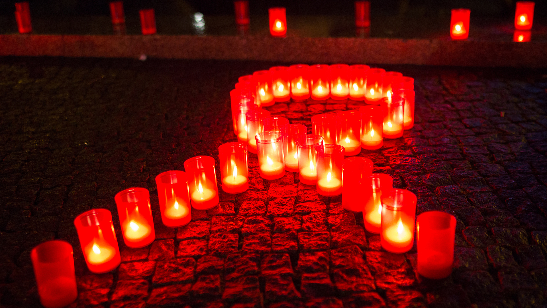 Kerzen bilden eine rote Schleife | picture alliance/dpa