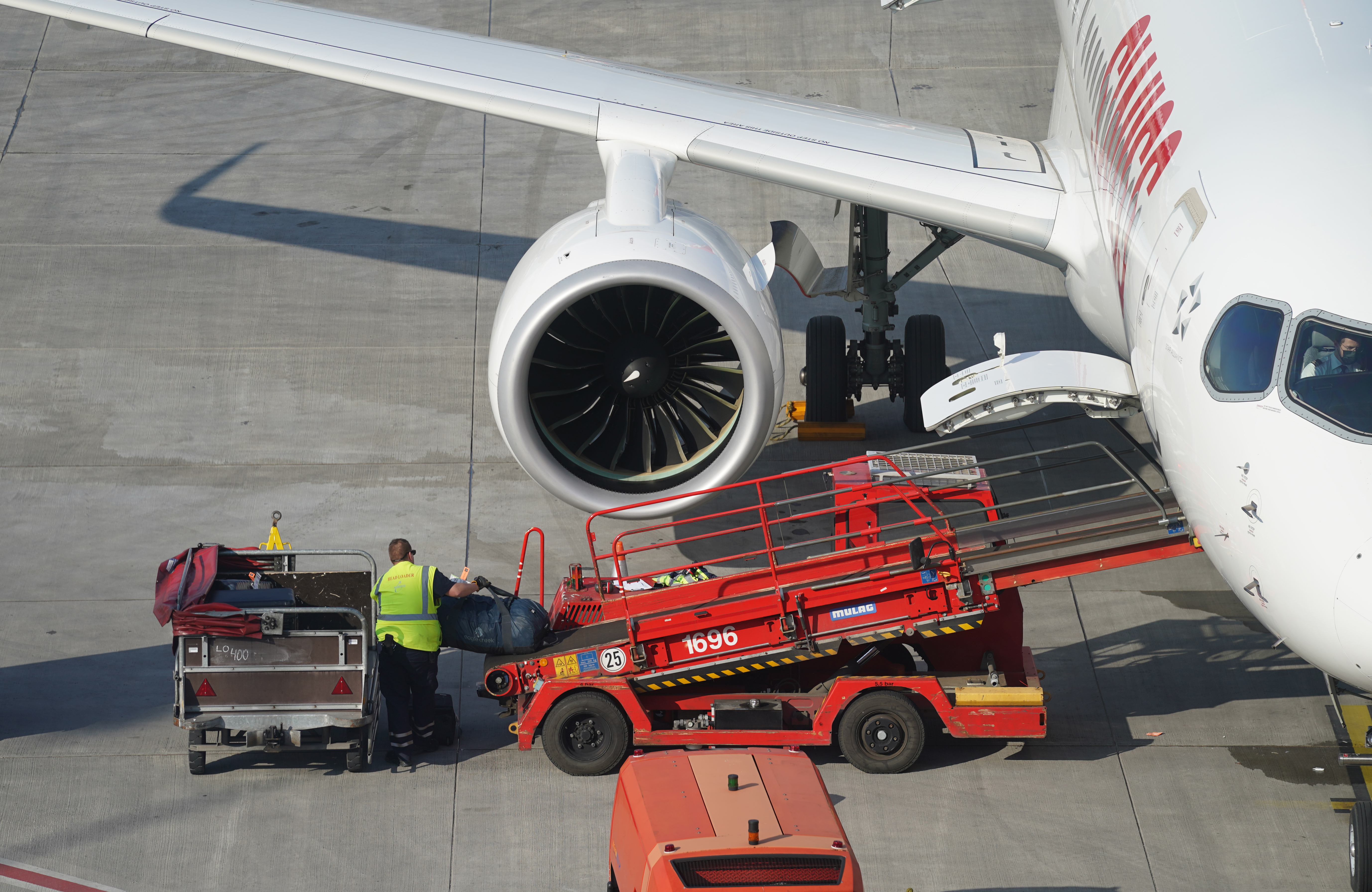 Flughafen-Mitarbeiter lädt auf dem Vorfeld eines Flughafens Gepäck aus einer Maschine | dpa