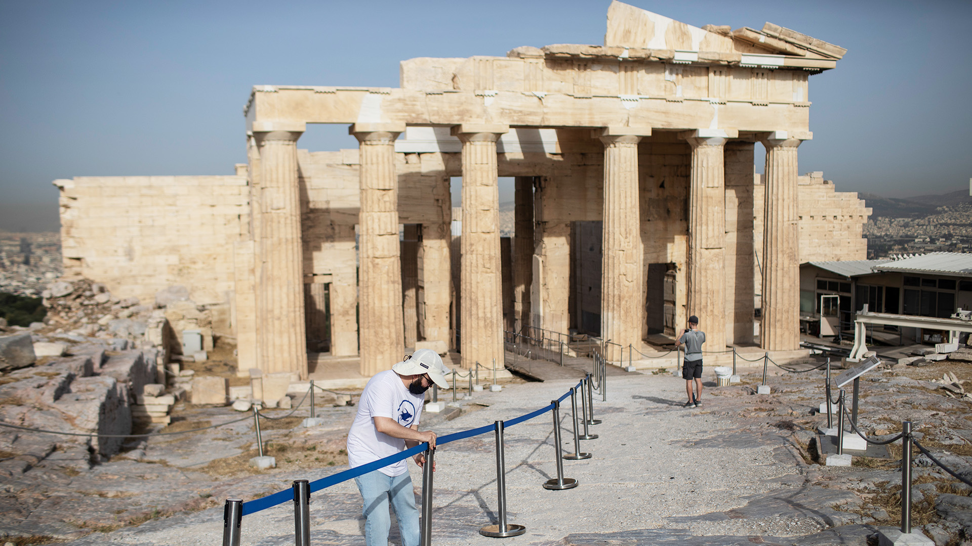 Ein Angestellter stellt Abgrenzungsständer für Besucher vor den Propyläen in der Athener Akropolis auf. | dpa