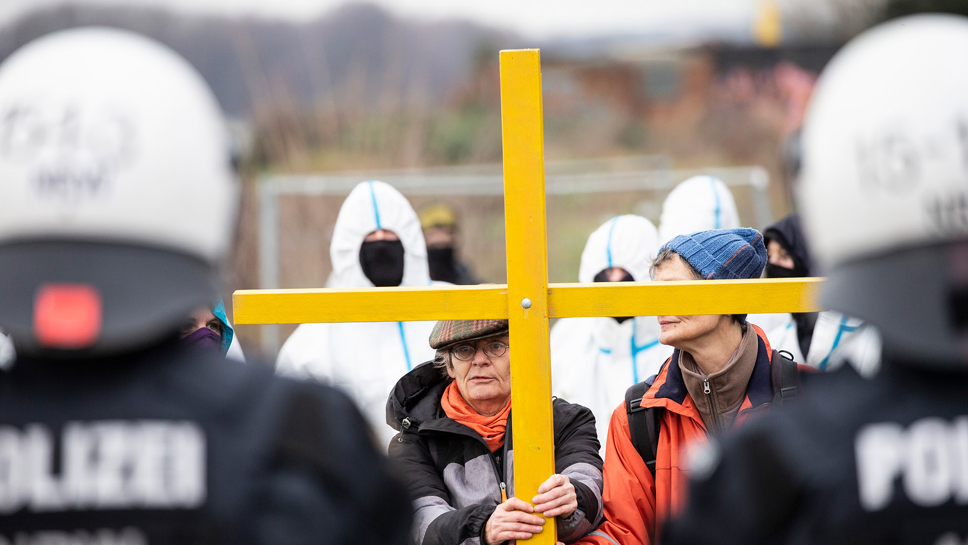 Polizisten stehen Aktivisten mit einem Holzkreuz gegenüber. | dpa
