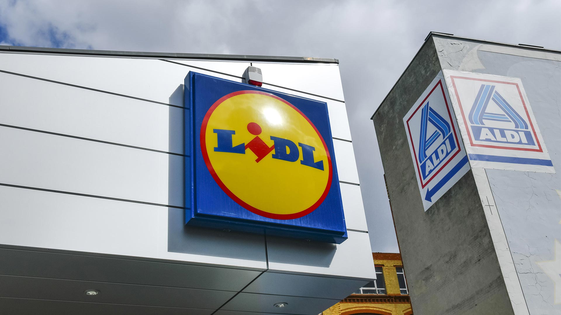 Die Logos von Aldi und Lidl hängen an zwei Filialen der Unternehmen in Berlin | picture alliance / picture allia
