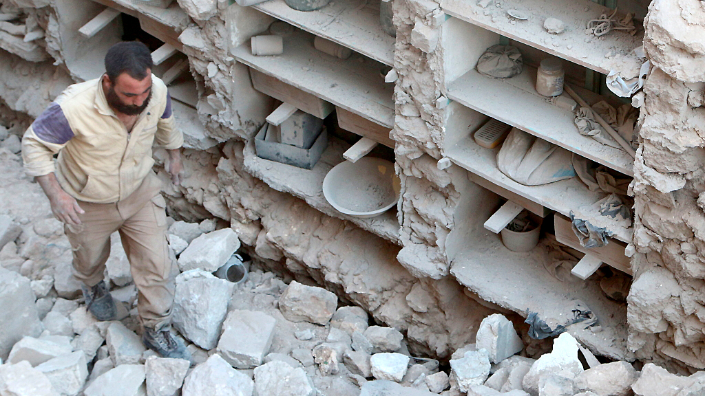 Ein Mann steht in einem zerstörten Haus in Aleppo.