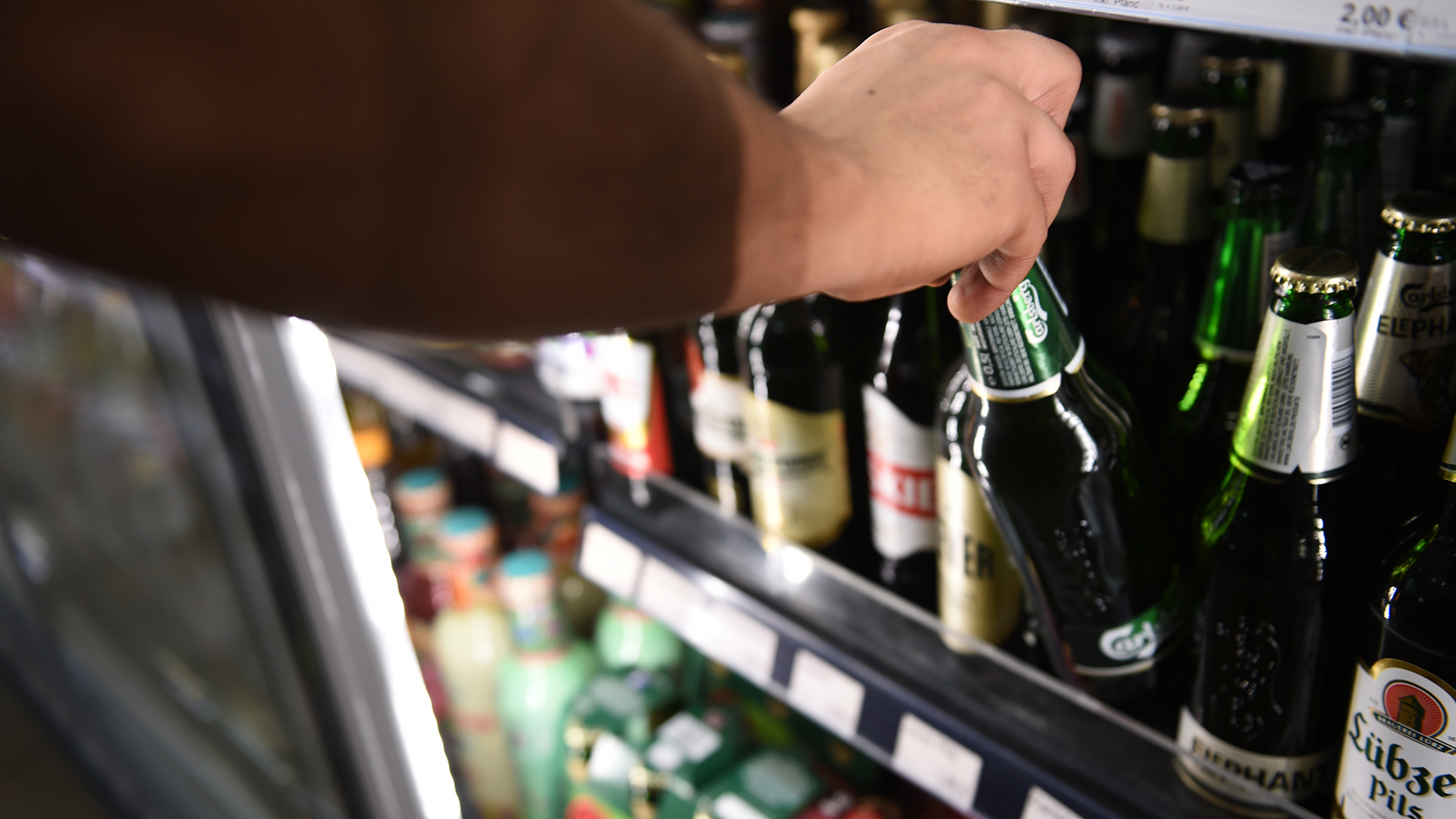 Ein Mann holt eine Flasche Bier aus einem Kühlschrank in einem Spätkauf. | dpa