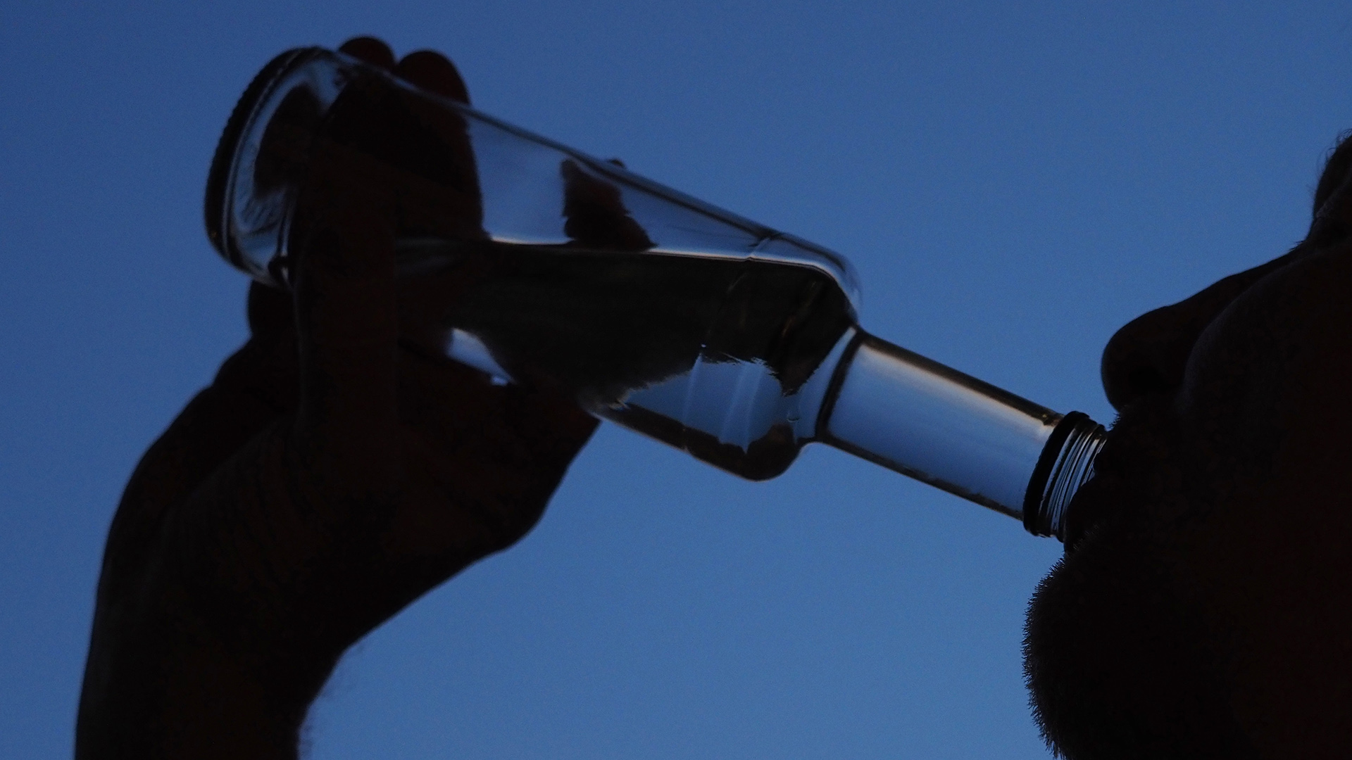  Ein Mann trinkt am Abend aus einer Flasche Schnaps.  | dpa