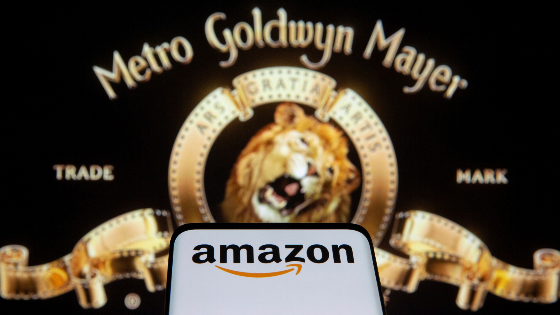 Smartphone mit Amazon-Logo vor MGM-Logo | REUTERS