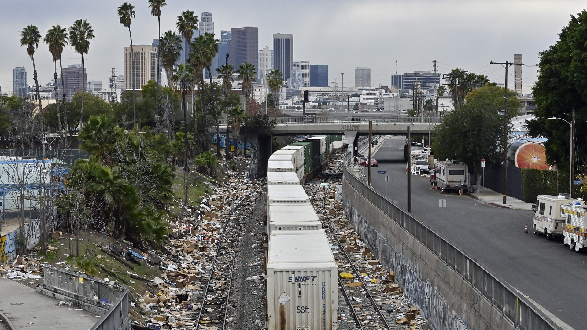 Ein Güterzug fährt nach Los Angeles - links und rechts der Gleise liegen aufgerissene Versandpakete. | picture alliance / newscom
