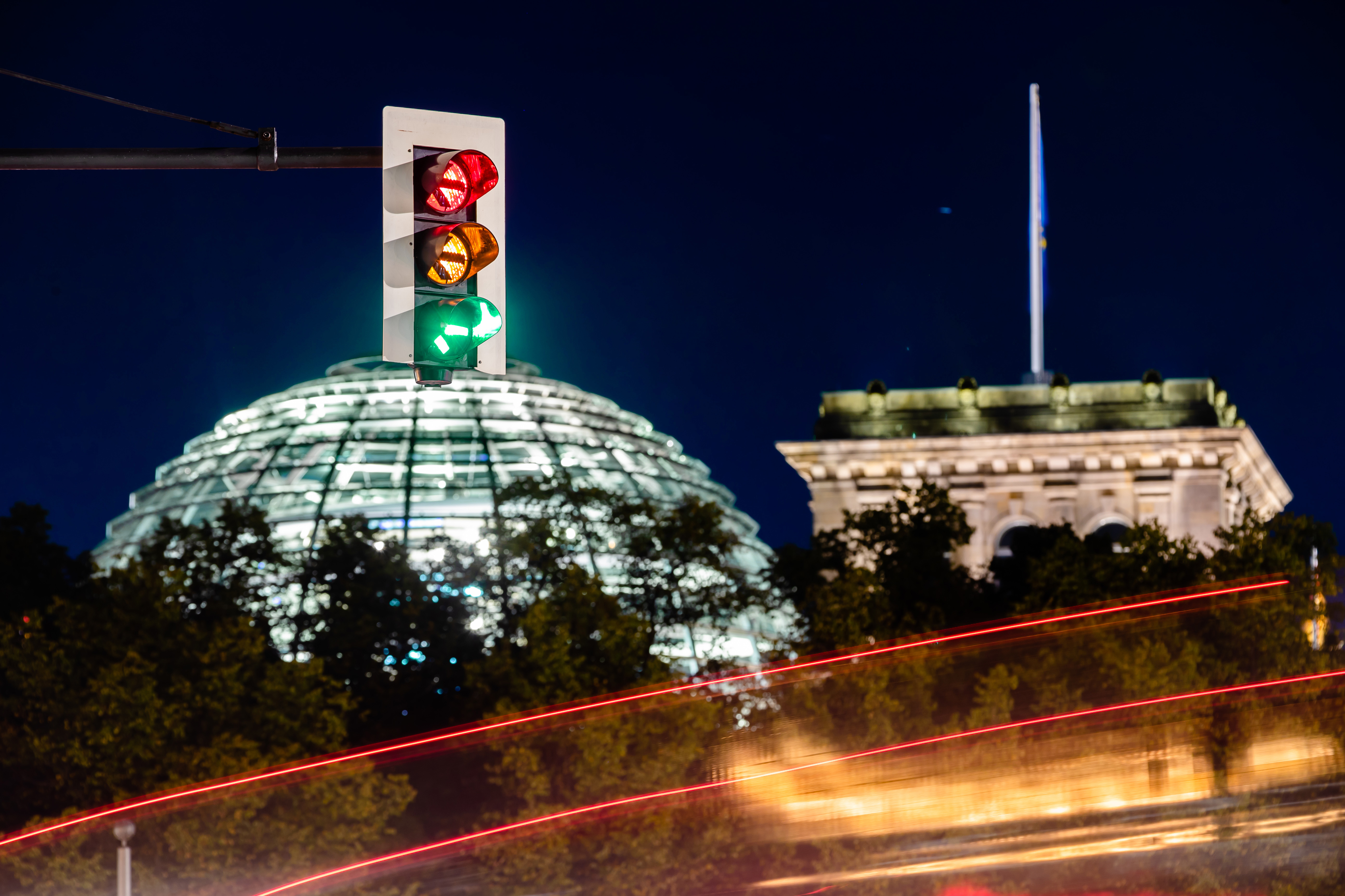 Eine Ampel vor dem Reichstagsgebäude leuchtet in einer Langzeitbelichtung in allen drei Phasen. | dpa