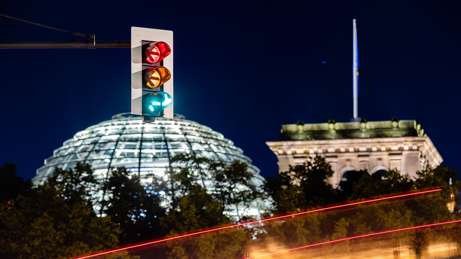 Eine Ampel vor dem Reichstagsgebäude leuchtet in allen drei Phasen.