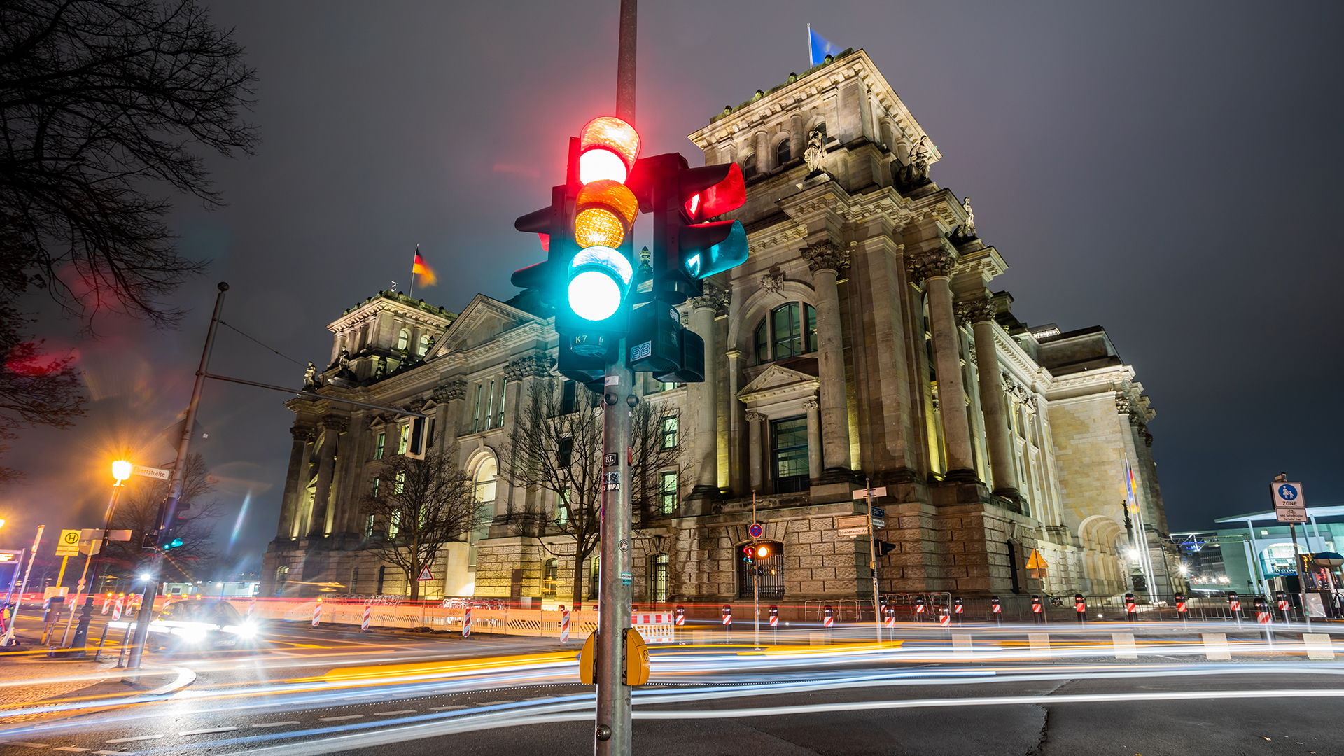 Eine Ampel leuchtet in einer Aufnahme mit Langzeitbelichtung am Morgen vor dem Reichstagsgebäude in allen drei Phasen. | dpa