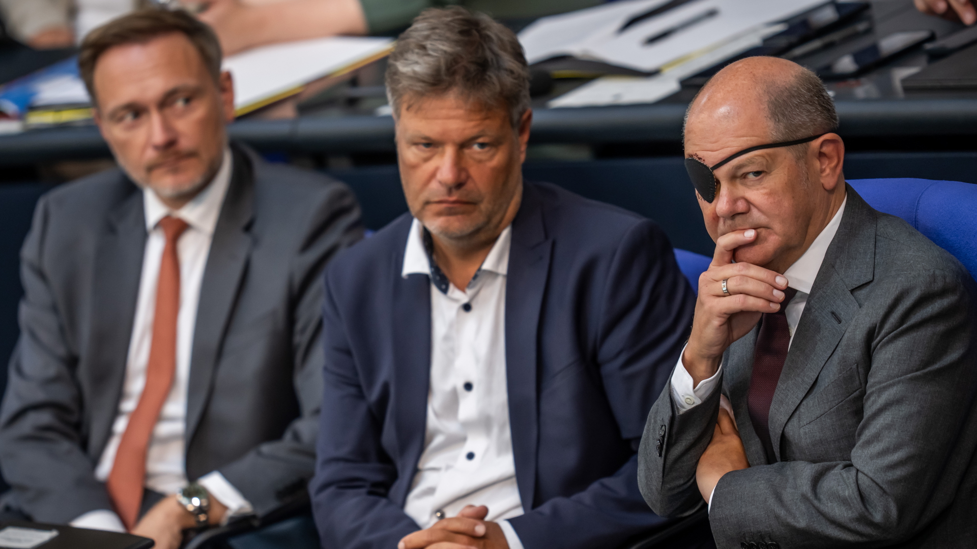 Sitzen während der Generaldebatte im September 2023 im Bundestag nebeneinander (von rechts): Bundeskanzler Olaf Scholz, nach einem Sturz mit Augenklappe, Wirtschaftsminister Robert Habeck und Finanzminister Christian Lindner.