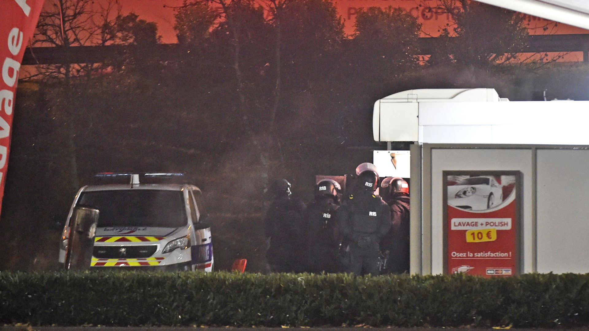 Eine Sondereinheit der französischen Polizei steht vor einer Autowaschanlage. | Bildquelle: AFP