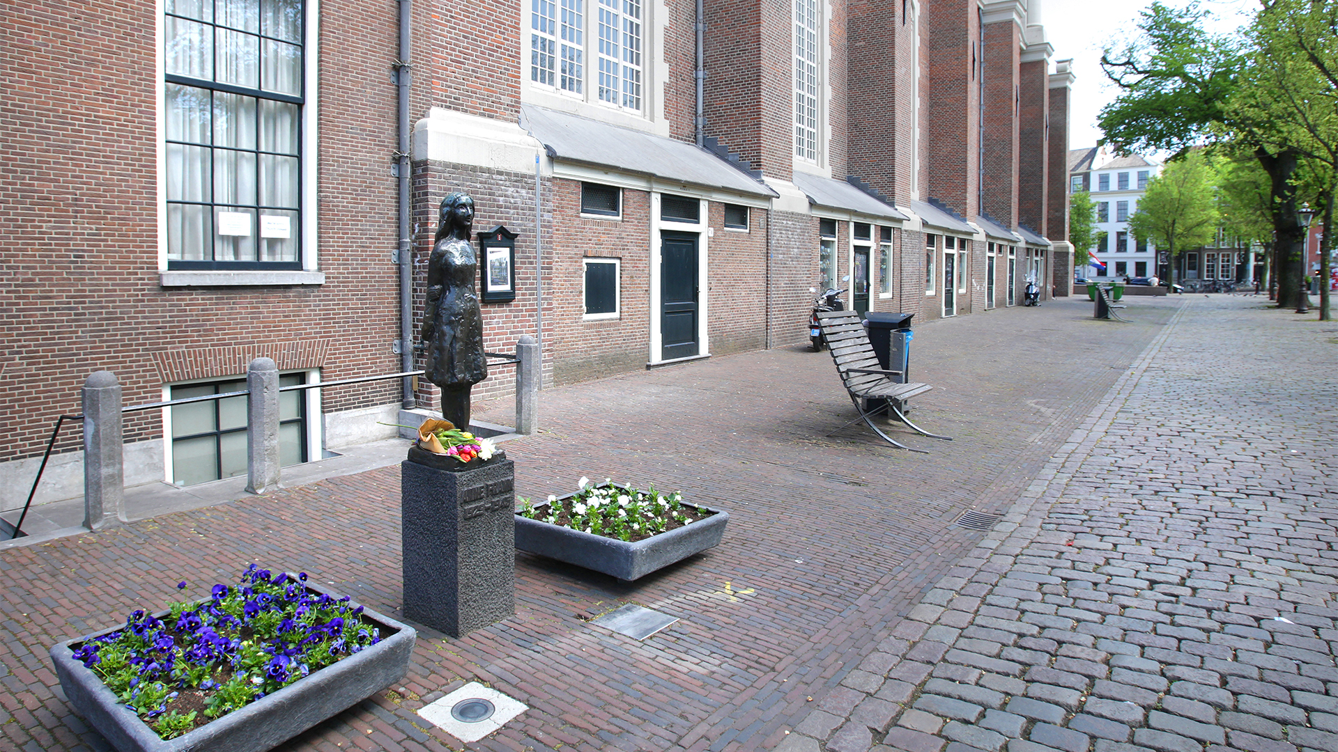 Blumen niedergelegt an der Anne-Frank-Statue in der Nähe des Anne-Frank-Hauses in Amsterdam (Niederlande).