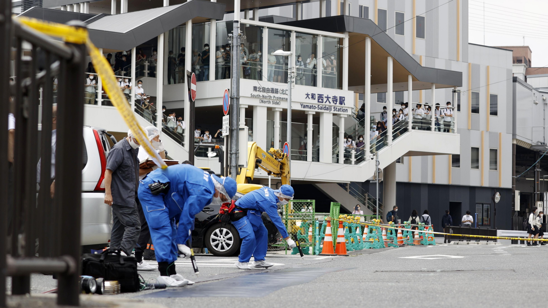 Polizisten in blauen Schutzanzügen sichern Spuren auf einer Straße in Nara - dem Ort, an dem ein Anschlag auf den früheren Premier Abe verübt wurde. | dpa