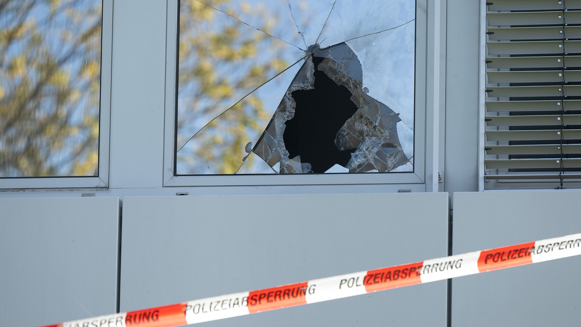 Ein Absperrband der Polizei hängt vor einer zerbrochenen Fensterscheibe einer geplanten Flüchtlingsunterkunft. | dpa