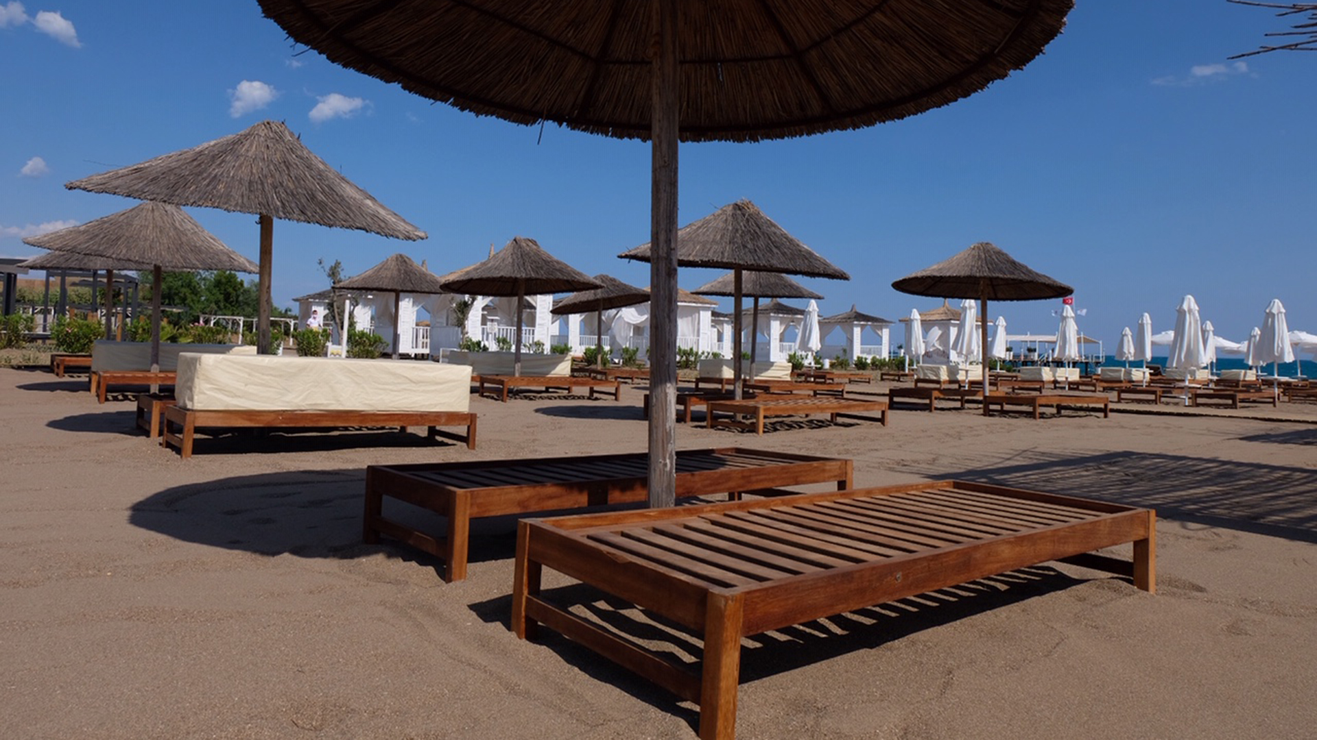 Strandliegen und Sonnenschirme stehen am menschenleeren Strand an einer Hotelanlage in Antalya. | dpa