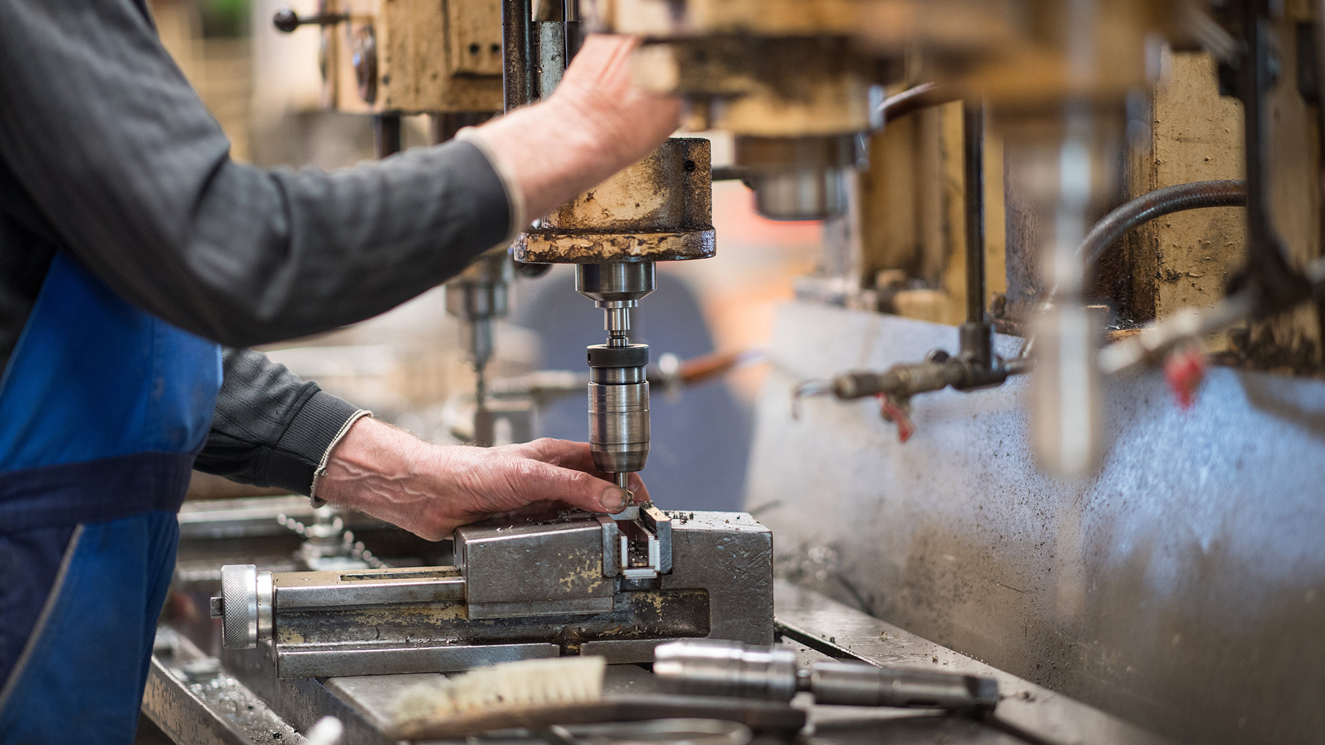 Ein Mitarbeiter bedient in der Produktionshalle einer Firma eine Maschine zur Verarbeitung von Metall.
