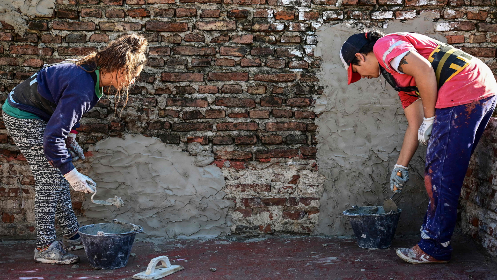 Zwei Argentinierinnen arbeiten an einer Mauer
