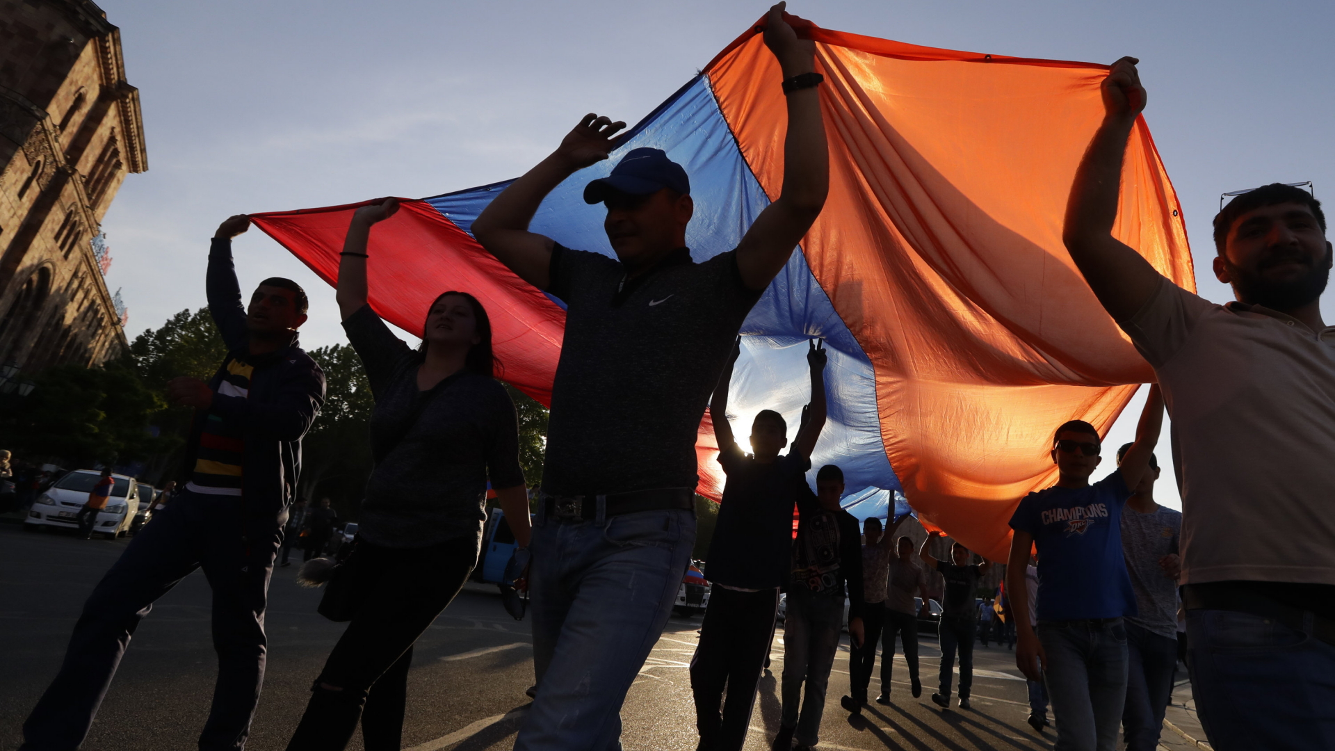 Teilnehmer einer Demonstration halten eine große Armenienflagge über ihre Köpfe. | dpa
