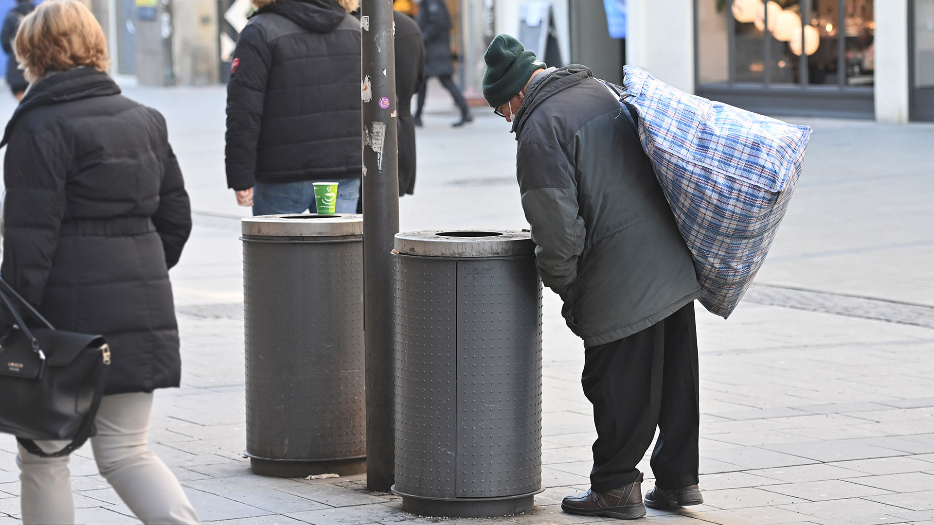Ein alter Mann blickt in einen Abfalleimer und sucht nach Pfandflaschen | picture alliance / SvenSimon