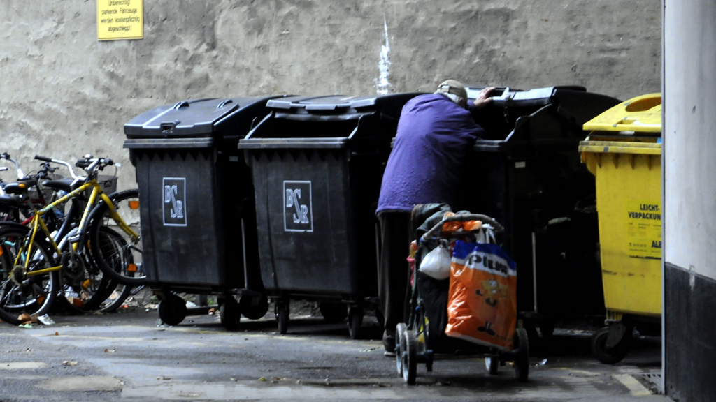 Ein Mann kramt in einer Mülltonne
