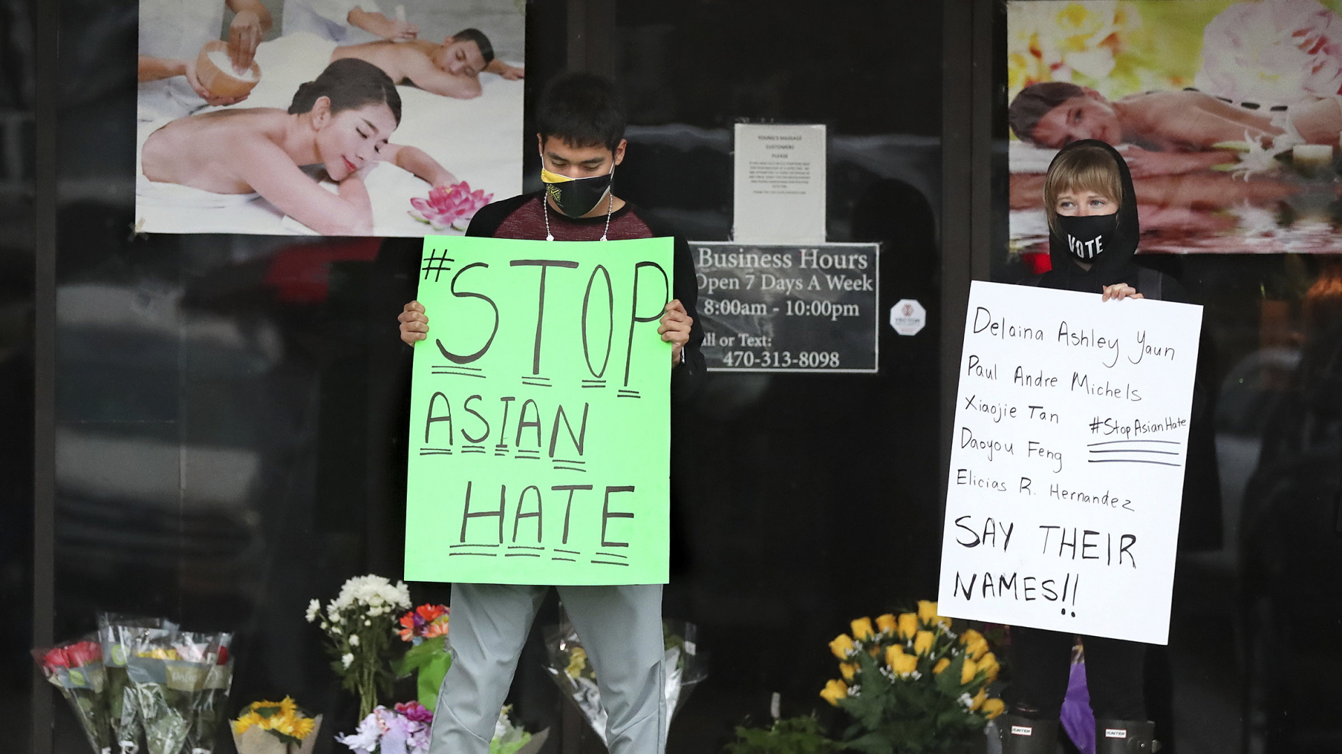 Zwei Personen stehen vor einem asiatischen Massagesalon in in Acworth und halten Protestschilder hoch. 