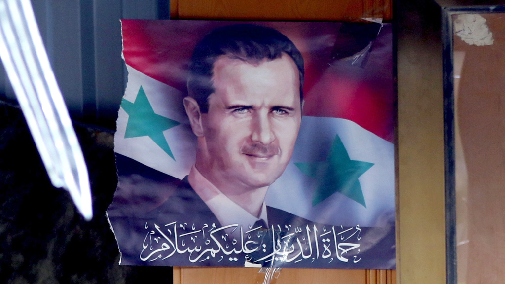 Poster des syrischen Präsidenten Assad hängt in einem schwer beschädigten Raum