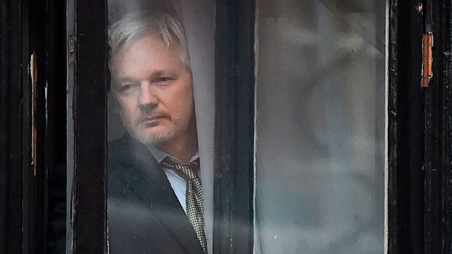 Wikileaks-Gründer Julian Assange schaut durch ein Fenster in der Londoner Botschaft von Ecuador. | AFP