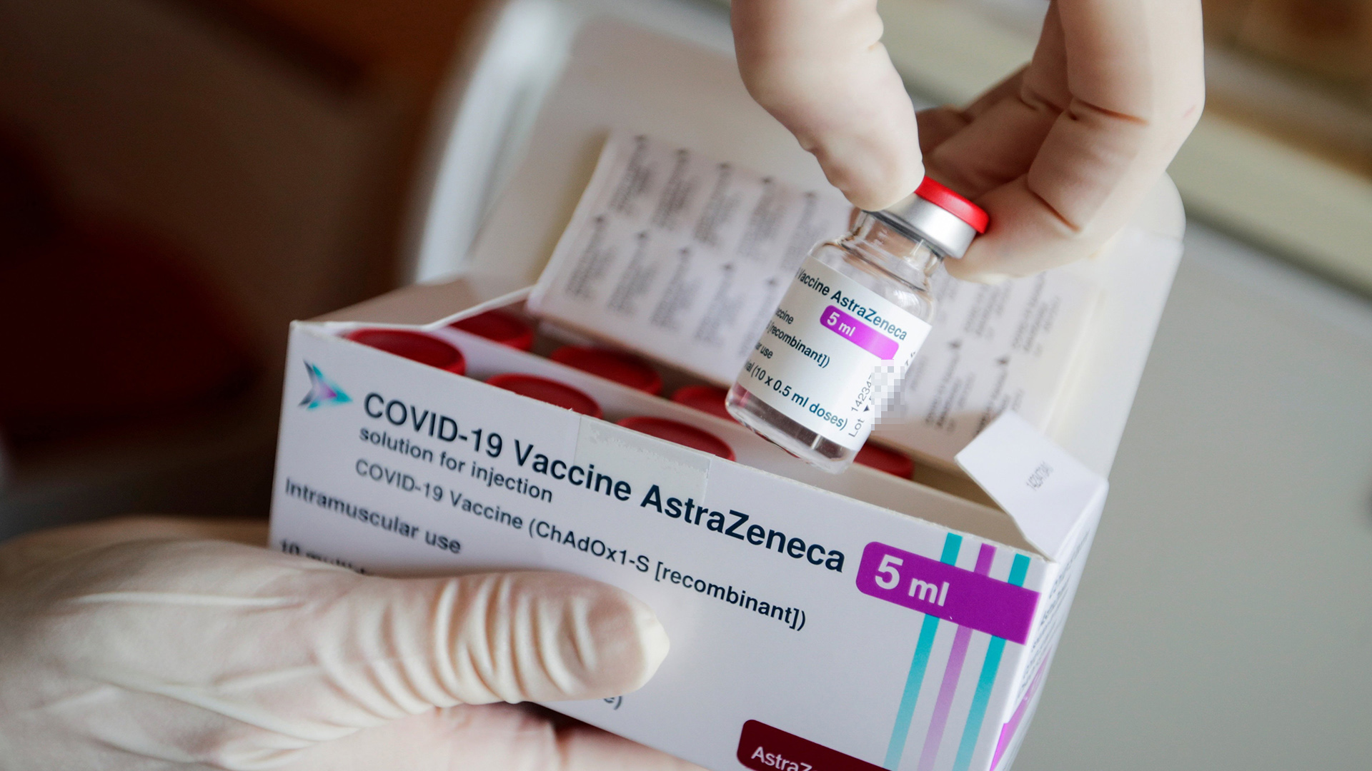 Eine Ampulle des Corona-Impfstoffs von AstraZeneca wird in einer Arztpraxis aus einer Packung entnommen. | dpa