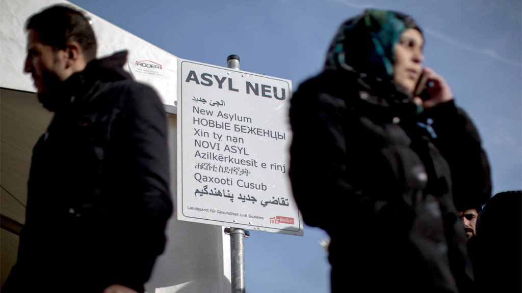 Flüchtlinge stehen vor dem Zelt mit einem Schild mit der Aufschrift "Asyl Neu" für neue Asylbewerber.