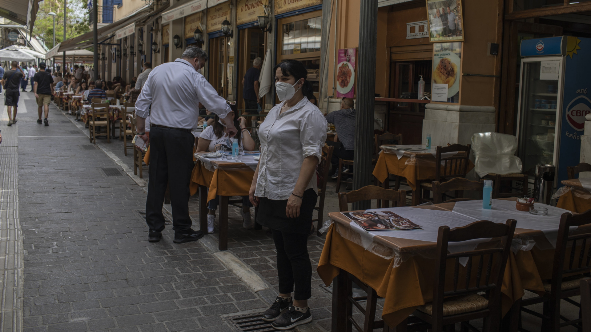 Eine Kellnerin mit Maske wartet vor einem wieder eröffneten Restaurant in Athen auf Gäste. | AP