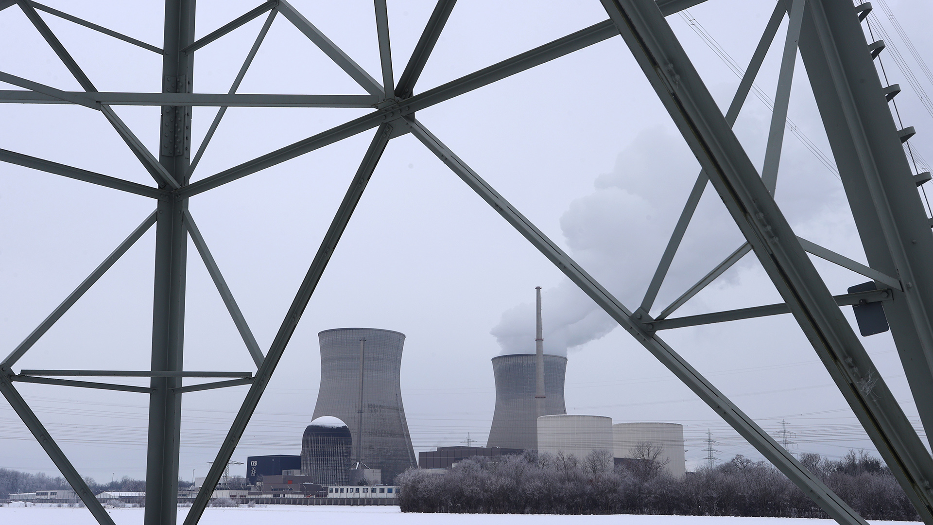 Kühltürme eines Atomkraftwerkes stehen hinter Strommasten.
