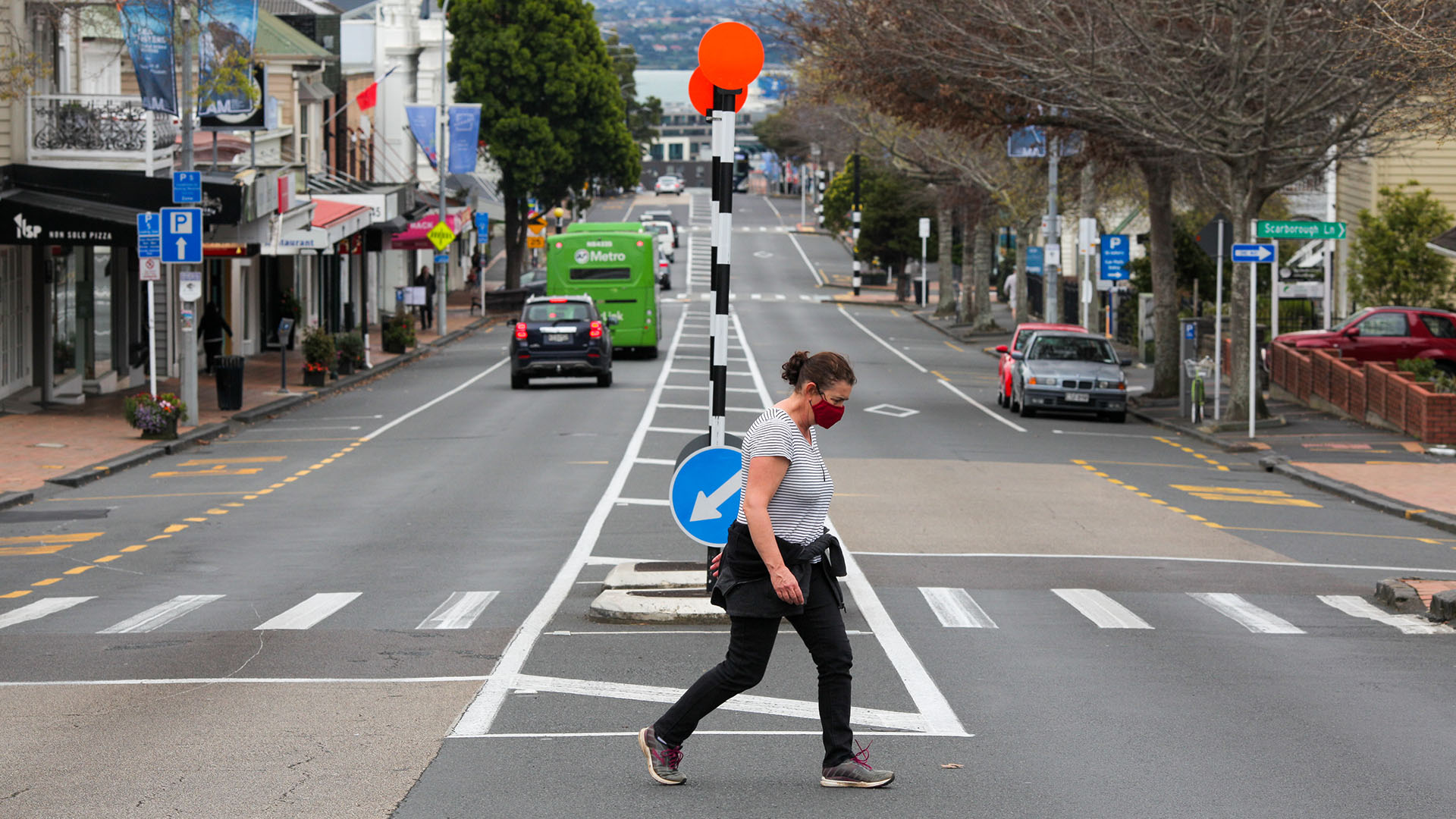 Ein Frau mit Mund-Nasen-Schutz überquert in Auckland eine Straße. | picture alliance / Xinhua News A