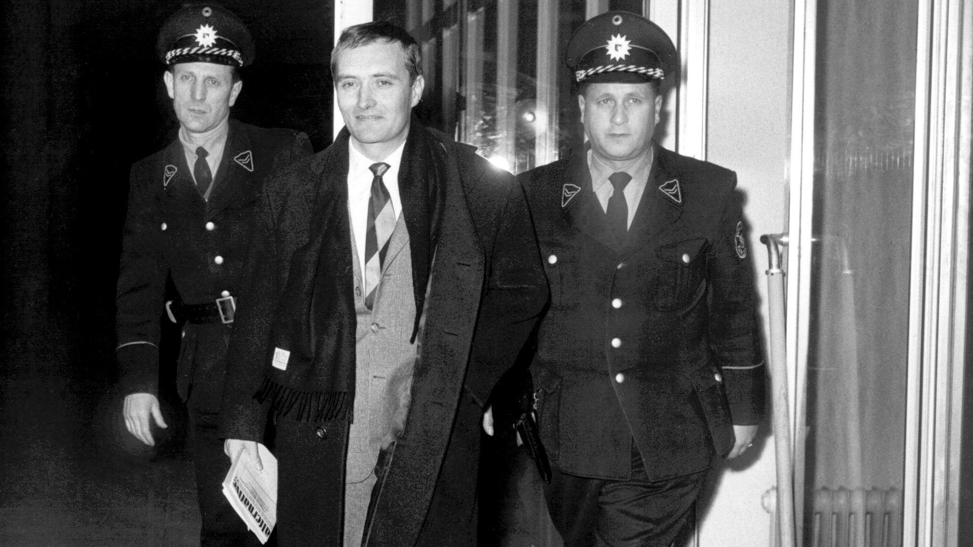 "Spiegel"-Herausgeber Rudolf Augstein (M) wird von zwei Polizeibeamten aus dem Gebäude des Bundesgerichtshofes in Karlsruhe geführt. (Archivbild: 08.01.1963) | picture-alliance/ dpa