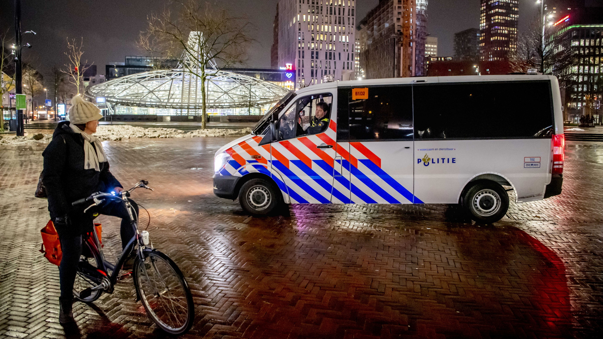 Polizisten im Streifenwagen sprechen eine Frau an, die am Abend noch in Rotterdam unterwegs ist. | dpa