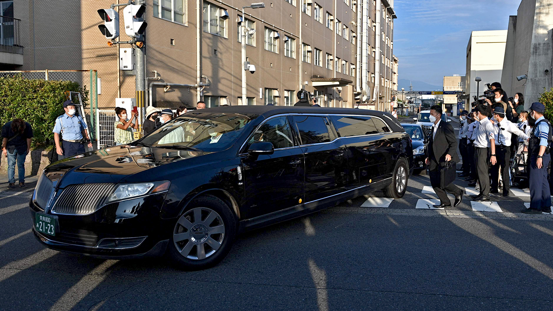 Das Auto, von dem angenommen wird, dass es die Leiche des verstorbenen ehemaligen japanischen Premierministers Shinzo Abe trägt, fährt an Polizisten und Medien vorbei | AFP