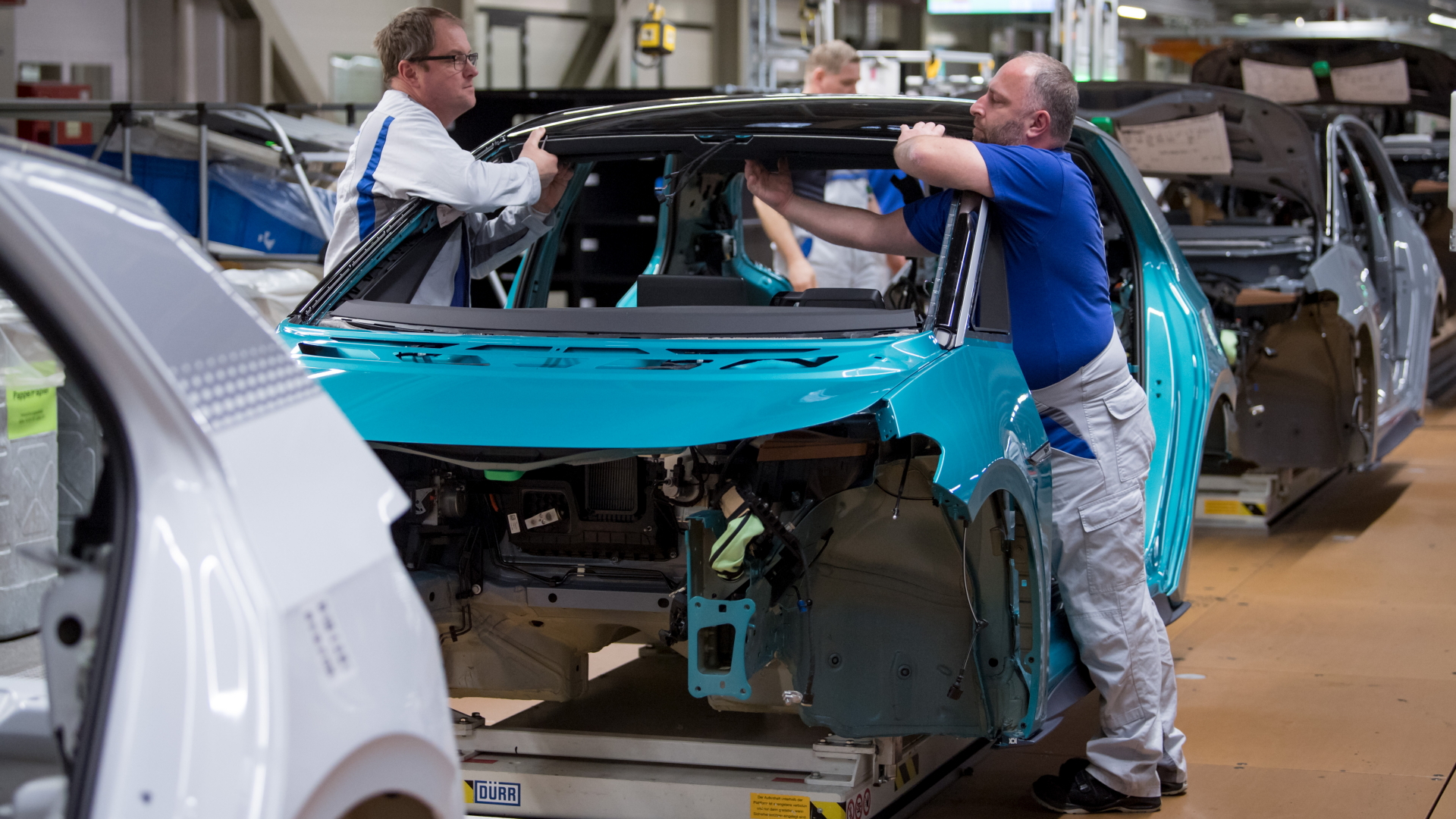Mitarbeiter des Volkswagen-Werks in Sachsen montieren den Dachhimmel eines Autos. | ZB