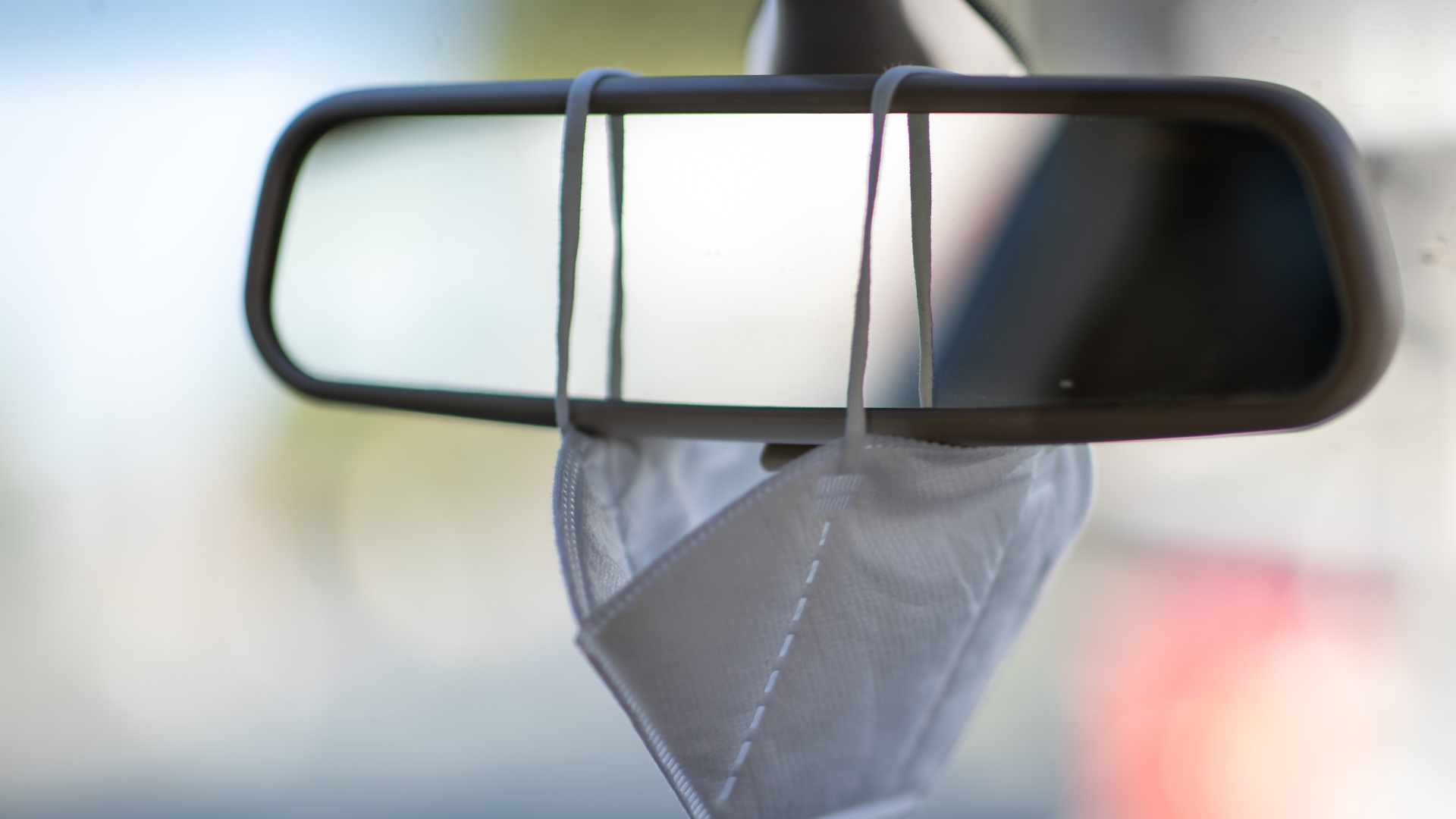 Eine FFP2-Maske hängt am Rückspiegel eines Autos. | dpa