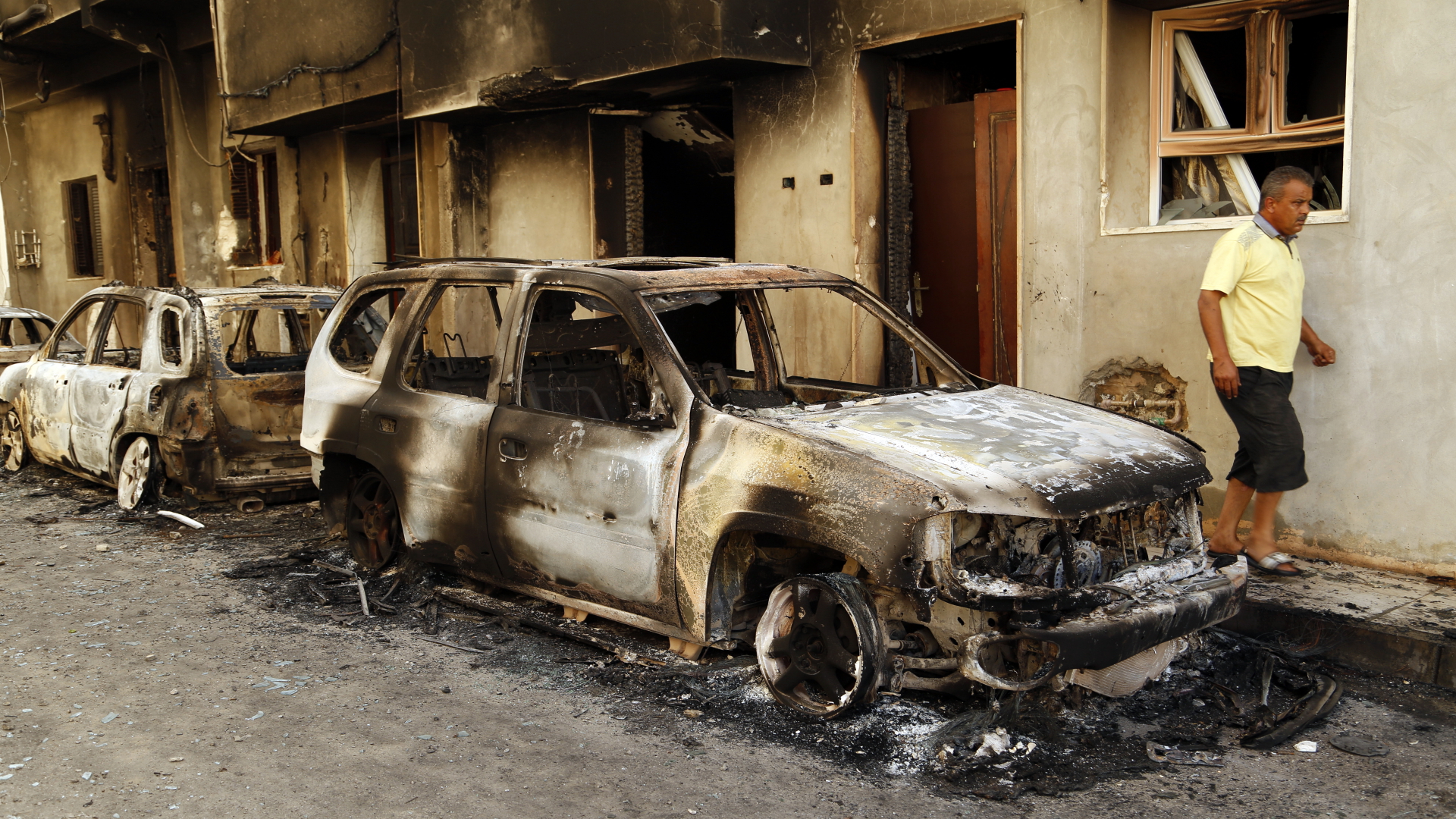 Die Überreste eines bei Zusammenstößen verbrannten Autos stehen auf einer Straße in Tripolis. | dpa