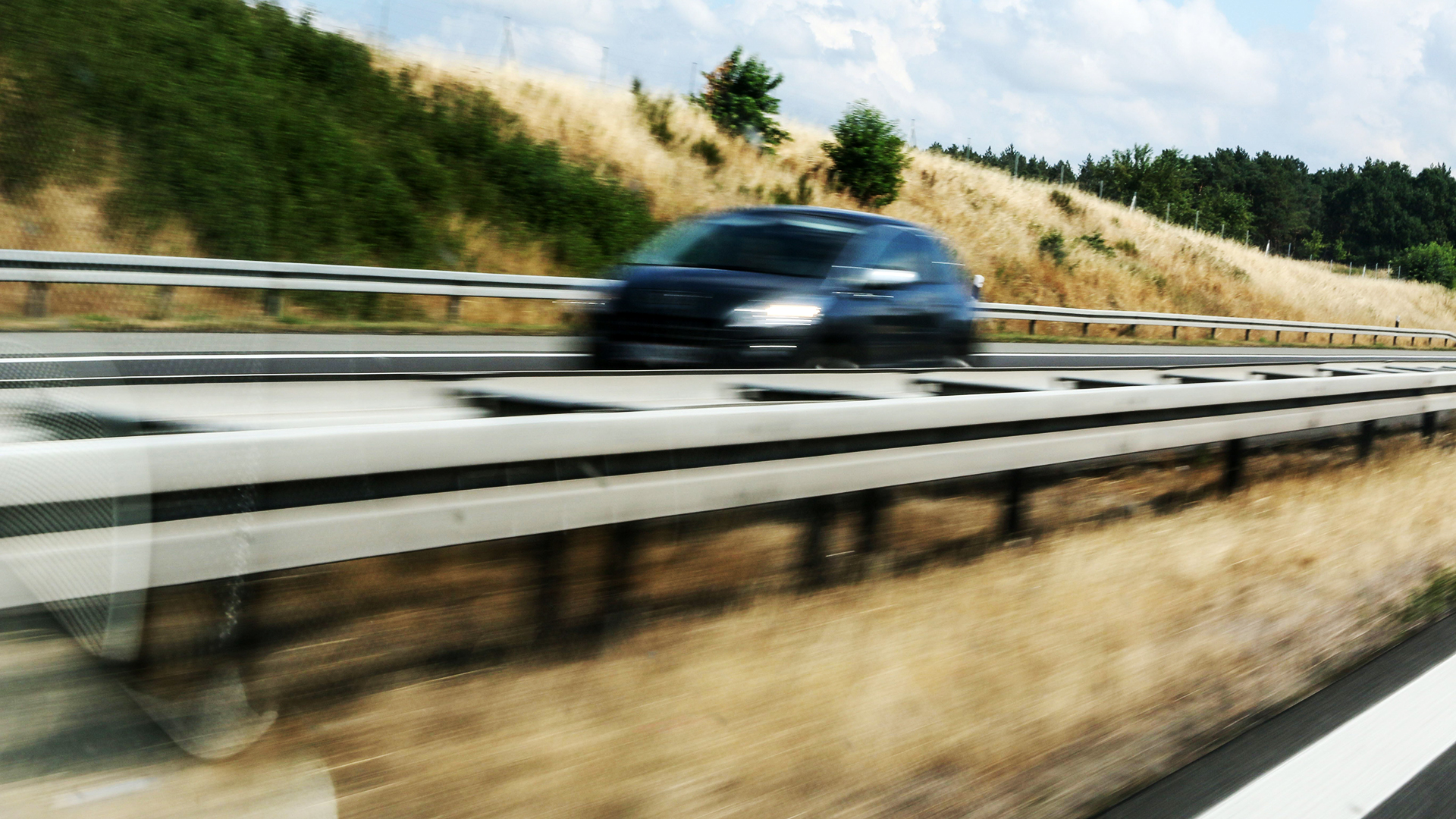 Ein schwarzes Auto fährt schnell auf einer leeren Autobahn. | picture alliance / Rolf Kremming