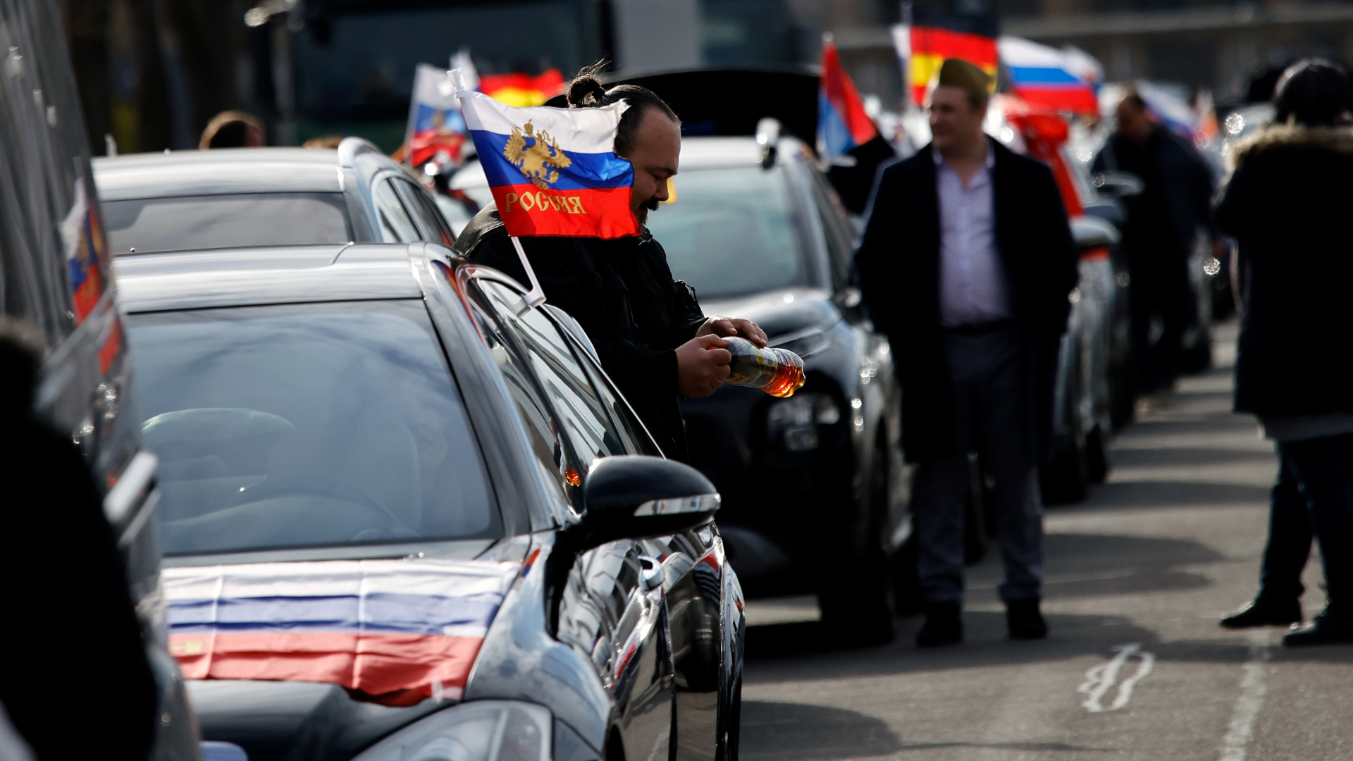 Faggen mit den russischen Nationalfarben und dem russischen Staatswappen wehen an einem Auto in Berlin. | dpa