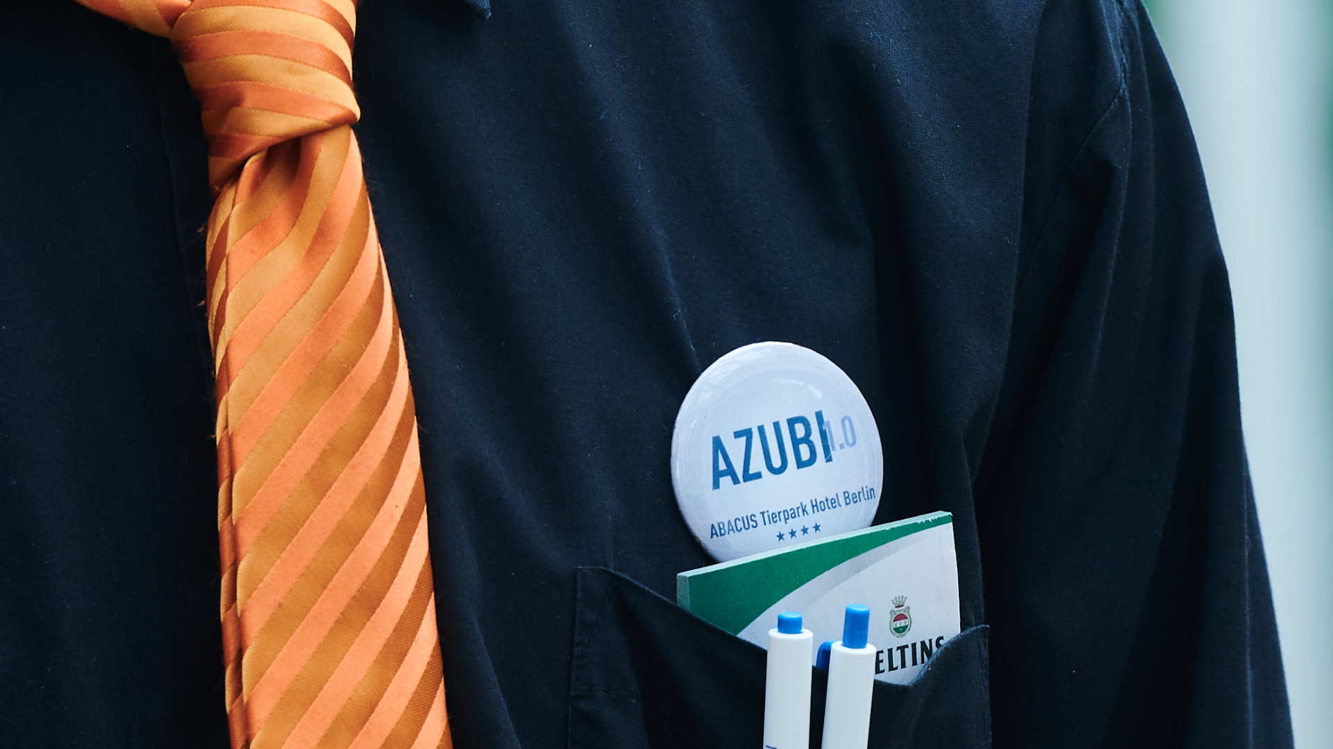  "AZUBI" steht auf dem Button eines Auszubildenden im Hotelfach. | dpa