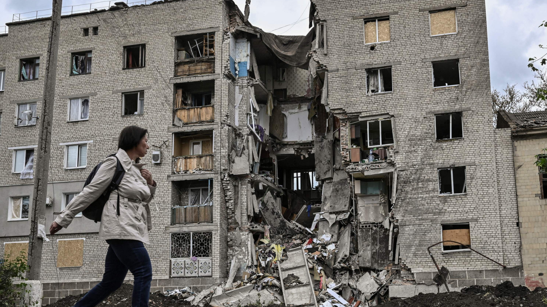 Eine Frau geht an einem zerstörten Wohngebäude vorbei | AFP