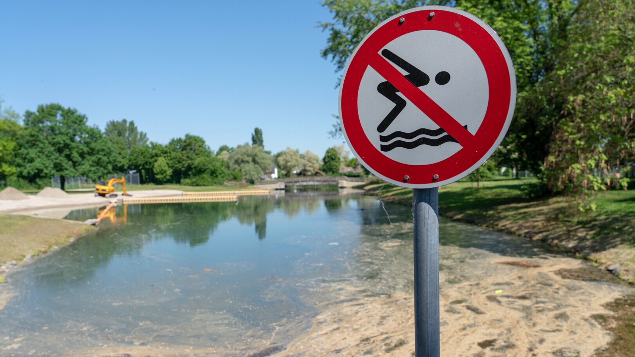 Ein Schild, das darauf hinweist, dass man an dieser Stelle nicht in den Badesee springen darf, steht vor dem Badesee Goldscheuer. (Archivbild) | dpa