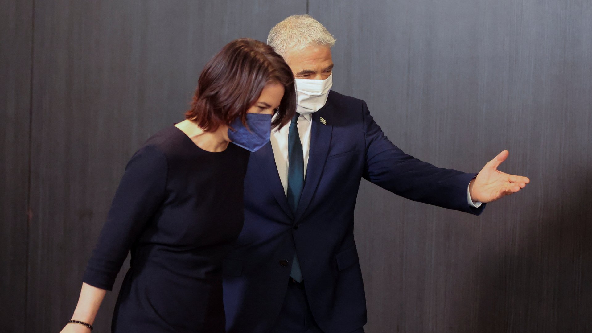 Bundesaußenministerin Annalena Baerbock und Israels Außenminister Jair Lapid auf dem Weg zur gemeinsamen Pressekonferenz im Februar 2022. Beide tragen Corona-Schutzmasken. | REUTERS