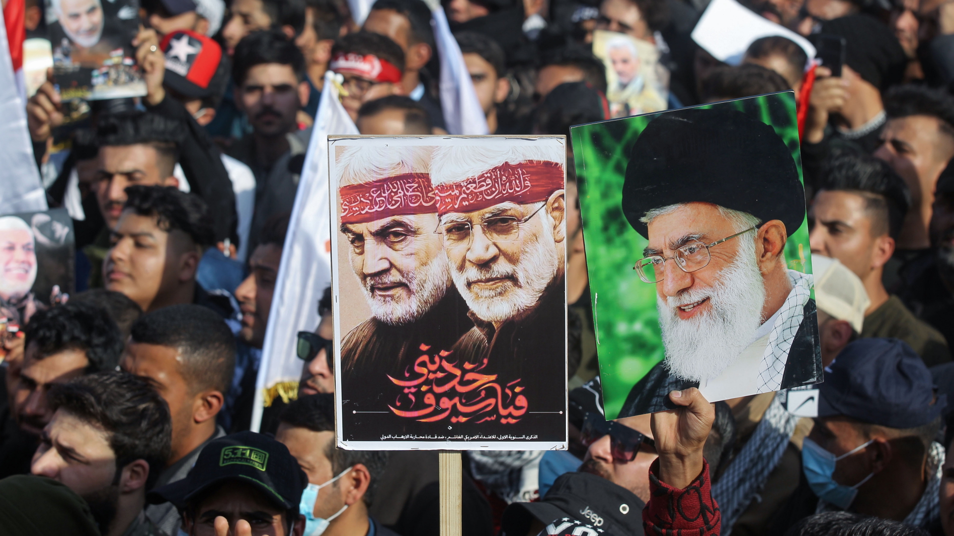 Ein Demonstrant in Bagdad trägt ein Plakat mit den Konterfeis Generals Soleimanis und des Milizenführer al-Muhandi.