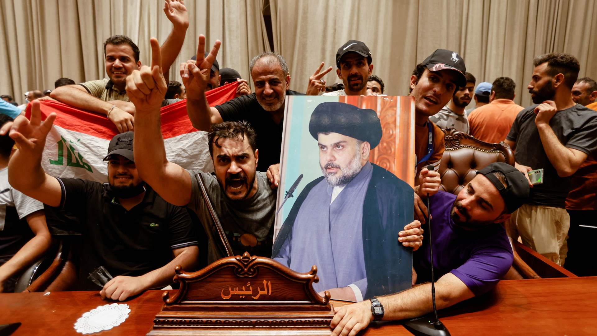 Schiiten besetzen das Parlament in Bagdad und halten ein Plakat des Predigers al-Sadr hoch. | REUTERS