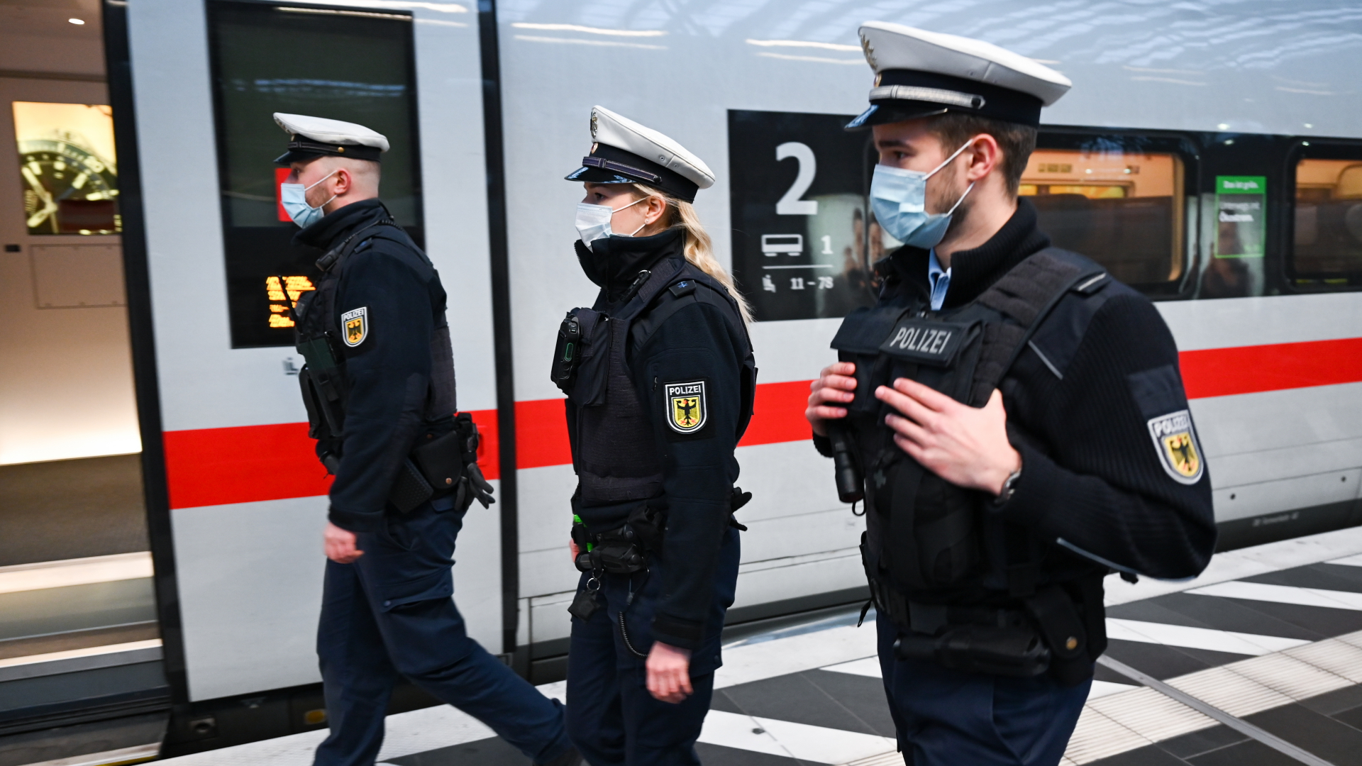 Bundespolizisten mit Mund-Nase-Bedeckungen laufen am Bahnsteig vor einem ICE der Deutschen Bahn. | dpa
