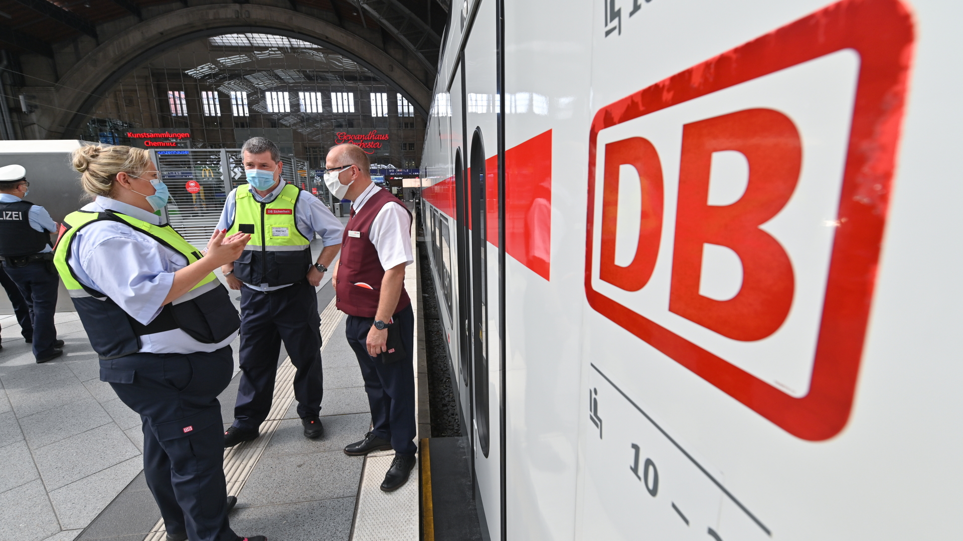 Ein Zugbegleiter zusammen mit zwei Mitarbeitern des Präventionsteams vor einem ICE im Leipziger Bahnhof. | dpa