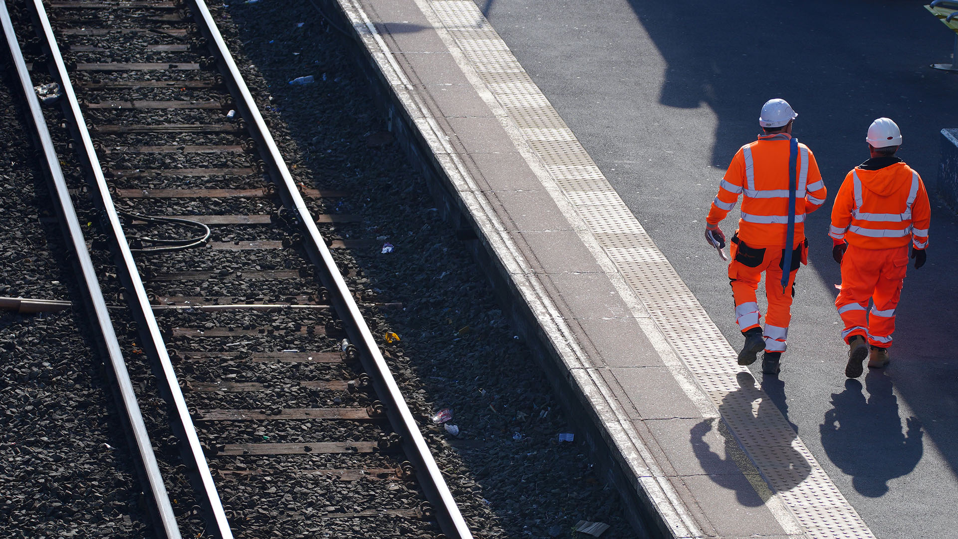 Bahnmitarbeiter in Warnkleidung gehen entlang eines Bahngleises im Bahnhof Hunts Cross, Großbritannien. | dpa