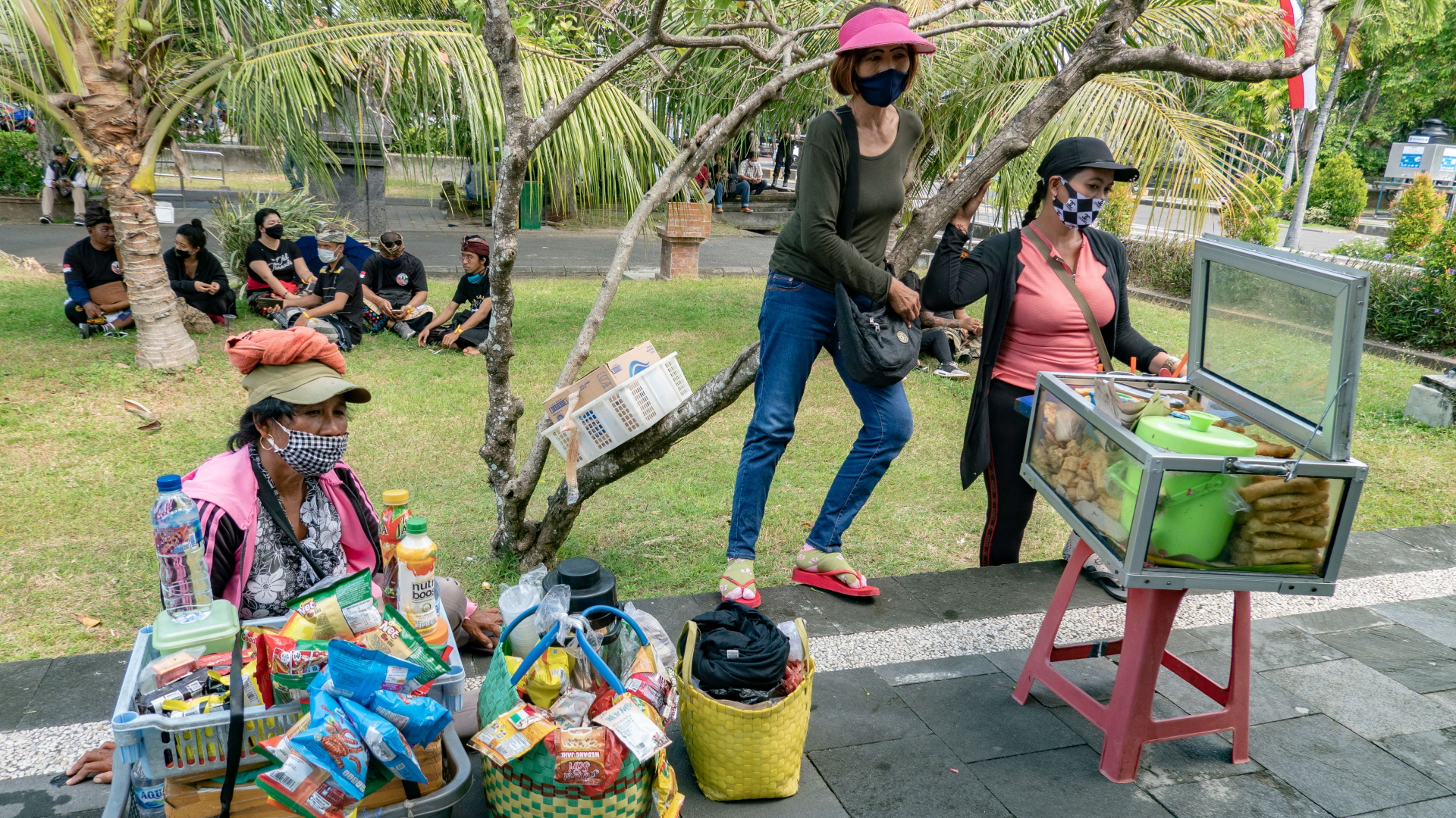 Mehrere Frauen mit Gesichtsmasken verkaufen Lebensmittel am Straßenrand. | MADE NAGI/EPA-EFE/Shutterstock